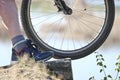 A bicycle wheel stands on a cliff above the quarry, next to a man`s leg. The cyclist over the precipice.