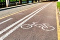 Bicycle white and yellow lanes sign and image of a bicycle with sun rays on road surface