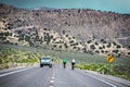 Bicyclers being passed by truck on two land Lonliest Highway in America through Nevada with scrub covered mountains in background