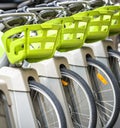 Bicycles with baskets for public rental stand at parking station in the row Royalty Free Stock Photo