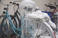 Bicycles covered with ice, big icicles and snow stand at parking near house Royalty Free Stock Photo