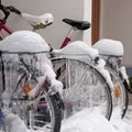 Bicycles covered with ice, big icicles and snow stand at parking near house Royalty Free Stock Photo