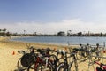 Bicycles parked on metal bike racks in the sand at Horny Corner Beach with blue ocean water and luxury homes, boats and yachts