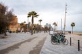 Bicycles at parking station and palm trees on promenade in La Barceloneta Beach