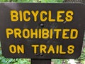 Bicycles prohibited on trails sign, yellow letters on brown sign