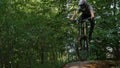 Bicyclist in safety helmet riding on mountain bike over springboard in forest