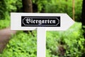 Biergarten Beer Garden in German white wood arrow direction sign with traditional German writing font. Sign in open air