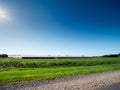 Big agriculture land by a road on a warm sunny day with clean blue sky. Food supply chain. Grain product production and Royalty Free Stock Photo