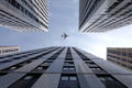 Big airplane flying high above modern city skyscraper buildings with many windows in business cluster view bottom up Royalty Free Stock Photo