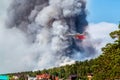 Big amphibious fire aircraft drops water on large forest fire near the village Royalty Free Stock Photo