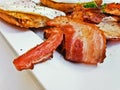 Big bacon in English breakfast with sunny fried eggs, bacon, tomatoes, ham on Turkish flat grilled bread on white dish