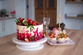 Big beautiful red velvet cake, with flowers and berries on top. Delicious sweet muffins with cream, Royalty Free Stock Photo