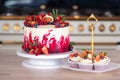 Big beautiful red velvet cake, with flowers and berries on top. Delicious sweet muffins with cream,