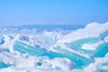 Big Beautiful turquoise blue ice on the Frozen Lake Baikal with mountains on the background. Royalty Free Stock Photo