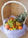 Big beautiful white basket of fruits, pineapple, peaches, tangerines, grapes, mangoes, apples, oranges, bananas