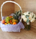 Big beautiful white basket of fruits, pineapple, peaches, tangerines, grapes, mangoes, apples, oranges, bananas