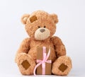 Big beige teddy bear with patches hold gift in boxe wrapped in brown paper