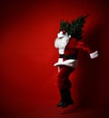 Fat Santa Claus carrying a heavy Christmas tree on his shoulder on a red background. New year and merry christmas