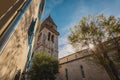 Big belltower of the Osor cathedral as seen on a cunny autumn day, with sun rays piercing through the leaves of a tree Royalty Free Stock Photo