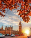 Big Ben against colorful sunset with autumn leaves in London, England