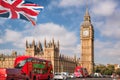 Big Ben with red buses on the bridge against flag of England in London, England, UK Royalty Free Stock Photo