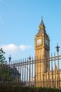 Big Ben tower in London behind fences with blue sky