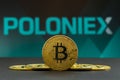 A big Bitcoin cryptocurrency coin in the centre and other bitcoin coins from both side in front of Poloniex crypto market . The