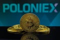 A big Bitcoin cryptocurrency coin in the centre and other bitcoin coins from both side in front of Poloniex crypto market . The