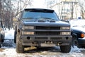 The big black jeep `Chevrolet Tahoe` with the winch costs parked in the yard.