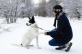 Big black-white dog is giving a paw its owner on a background of winter snowy forest Royalty Free Stock Photo