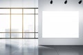 Big blank white illuminated billboard with place for your advertisement on light wall in sunlit empty hall with grey floor and Royalty Free Stock Photo