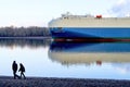 Big blue cargo ship carrying vehicles sailing in the tranquil lake against a cloudy sky