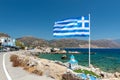 Big blue Greek flag and small church at coast of Palaiochora town on Crete island, Greece Royalty Free Stock Photo