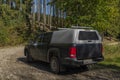 Big blue off-road car with white roof in color autumn forest in mountains Sumava