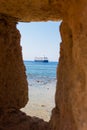 Big blue ship seen through an opening in a stone wall. View of sailboat sailing in the Chania Crete through a window in a wall. Ho Royalty Free Stock Photo