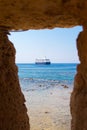 Big blue ship seen through an opening in a stone wall. View of sailboat sailing in the Chania Crete through a window in a wall. Ho Royalty Free Stock Photo