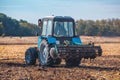 Big blue tractor plows the field and removes the remains of previously mown corn. Royalty Free Stock Photo