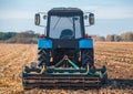 Big blue tractor plows the field and removes the remains of previously mown corn. Royalty Free Stock Photo