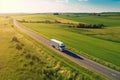 Big blue truck driving fast with a white trailer with blank space for text on a countryside road with other cars against