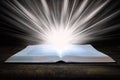 The big book of the Bible lies on a wooden table. In the dark. A light shines on the book from above. Light comes out of the book Royalty Free Stock Photo