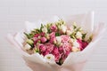 Big bouquet of beautiful and bright white-pink roses and eustoma in pink packaging on a white wall background. close-up Royalty Free Stock Photo