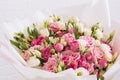 Big bouquet of beautiful and bright white-pink roses and eustoma in pink packaging on a white wall background. close-up Royalty Free Stock Photo