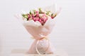 Big bouquet of beautiful and bright white-pink roses and eustoma in pink packaging on a white wall background Royalty Free Stock Photo