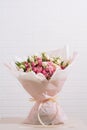 Big bouquet of beautiful and bright white-pink roses and eustoma in pink packaging on a white wall background Royalty Free Stock Photo