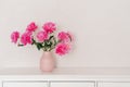 big bouquet of fuchsia peonies in a pink vase in a bright room are on a white chest of drawers. cozy house, fresh flowers at home,