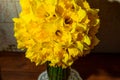 A big bouquet of yellow daffodils in a vase on a wooden table Royalty Free Stock Photo