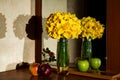 A big bouquet of yellow daffodils in a vase on a wooden table, with apples Royalty Free Stock Photo