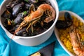 Big bowl with boiled black mussel and shrimp and small plate with paella