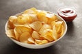 Big bowl with crispy potato chips and tomato dip sauce on table. Royalty Free Stock Photo