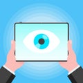 Big brother concept. Hands holding stablet pc spying with big eye on the screen isolated on light blue background